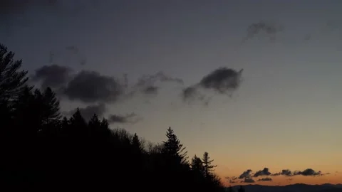 Clouds Moving Across Predawn Sky over Fir Trees in the Mountains Video stock 232684694