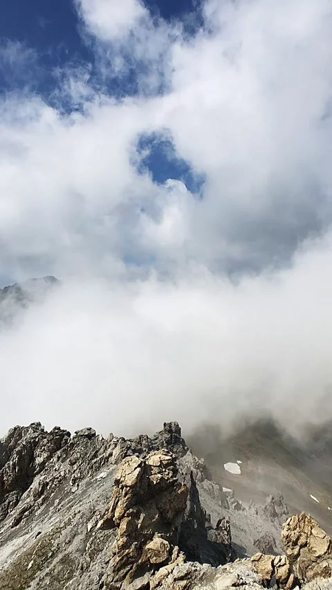 Clouds moving around rocky alpine peaks and ridges in a slow-motion manner Stock Footage 248057783