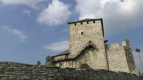 Clouds moving in a blue sky over the medieval stone tower Stockbeeldmateriaal 243386219