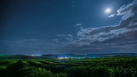 Clouds moving over green landscape at night Stock Footage 72985204