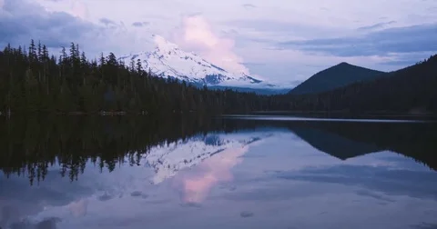 Clouds moving over the lake, forest and snowcapped mountain Stock Footage 77768559