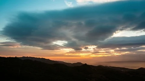 Clouds moving over mountain range during sunset Stock Footage 77548733