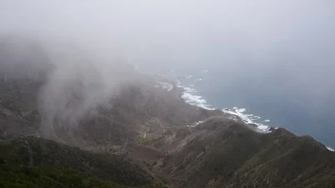 Clouds moving over the mountains with the ocean in the background at Anaga in Video stock 135661574