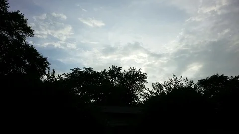 Clouds moving over quaking tree tops and roof line as the sun goes down Stock Footage 94132365