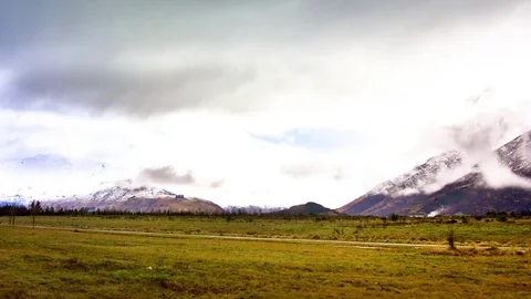 Clouds moving over snow covered mountains and green landscape Stock Footage 76105966