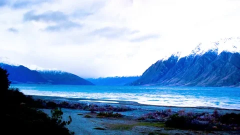 Clouds moving over snow covered mountains and Wanaka lake Stock Footage