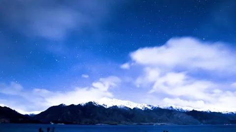 Clouds moving over snow covered mountains and Wanaka lake Stock Footage 76106142