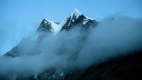 Clouds moving over the snow covered mountain peak Stock Footage 77452306