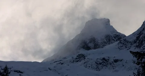 Clouds moving over the snow covered mountains Stock Footage 77765512