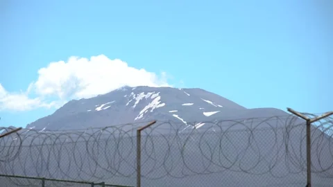 Clouds that moving over the snowy mountain behind the prison wires Stock Footage 142958385
