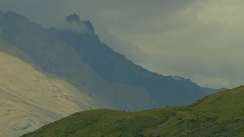 Clouds moving past dark mountain peak foreground hill Stock Footage 159751138