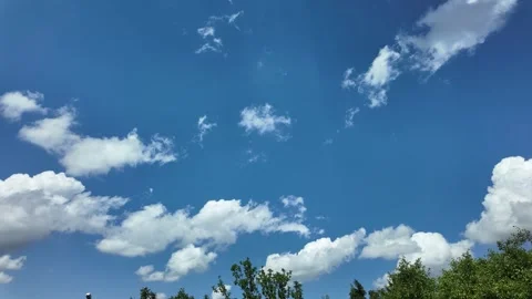Clouds moving in the sky with trees visible below during a bright day Stock Footage 339800941
