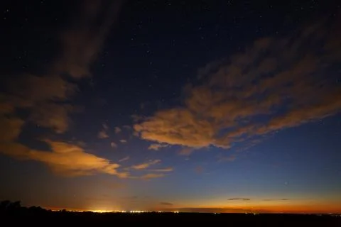 Clouds at night against the background of bright stars in the sky after sunse Stock Photos