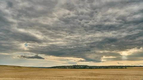 Clouds over an agricultural field. A spring landscape with a forest, an empty Stock Photos