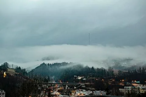 Clouds over broadcasting tower on the top of the hill. Foggy weather Foto stock
