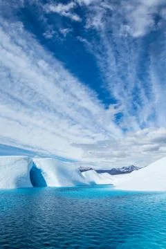 Clouds over deep blue glacial lake and ice cave on the Matanuska Glacier in A Stock Photos