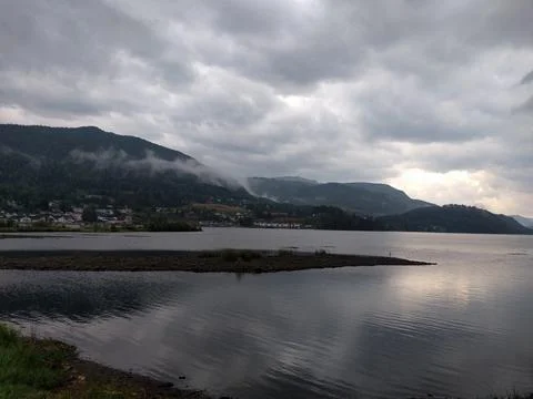 Clouds over the lake with view of small town Stock Photos