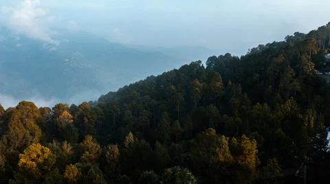 Clouds over the mountains with green trees Stock Photos