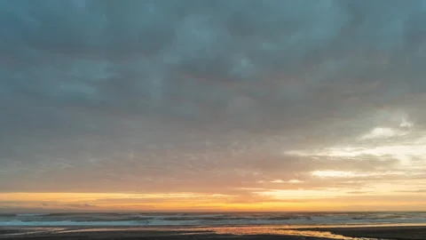 Clouds over an ocean beach during a yellow sunset - timelapse Stock Footage 220666535
