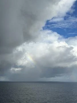 Clouds over ocean with rainbow Stock Photos