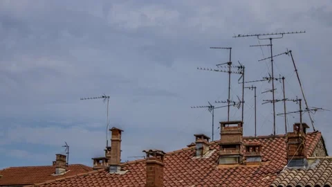 Clouds over red tiles and analog antennas in southern France Stock Footage 137950576
