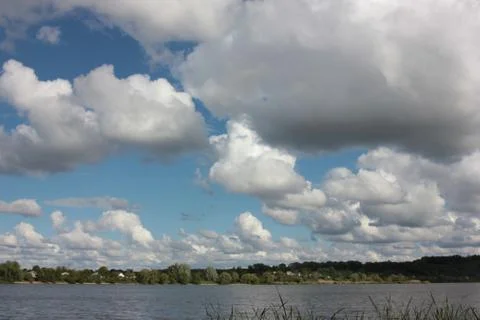 Clouds over the river. Summer landscape with low cloudy sky and green trees Stock Photos