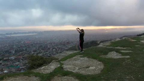Clouds over small town and woman standing on canyon edge Stock Footage 131030846