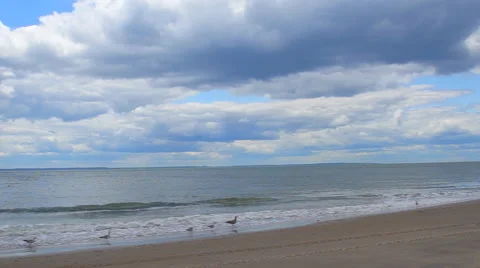 Clouds over waves touching sandy beach Stock Footage 63998198