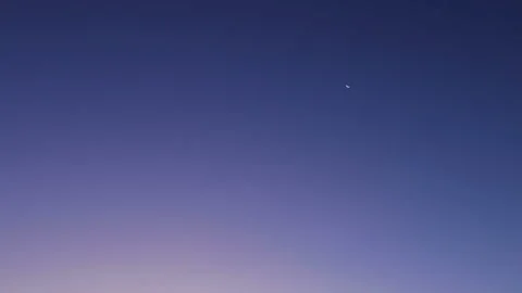 Clouds pass in front of the waning crescent moon as it moves slowly across the Stock Footage 94313618