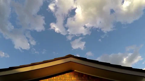 Clouds pass over a rooftop of a suburban home. Time Lapse zoom in. Stock-Footage 63014883