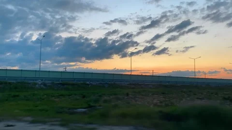 Clouds passing by during a colorful sunset over highway Stock Footage 305030858