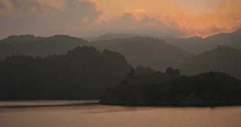 Clouds passing by a mountainous landscape and an orange sky Vidéo 263036654