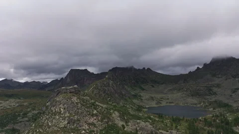 Clouds passing over mountain lake and green valley on cloudy day Stock Footage 300931513