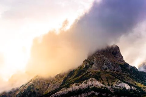Clouds passing over a mountain at sunset Stock Photos