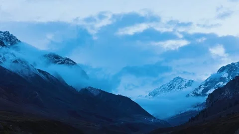 Clouds passing over snow dsted summit at sunset Stock Footage 330440058