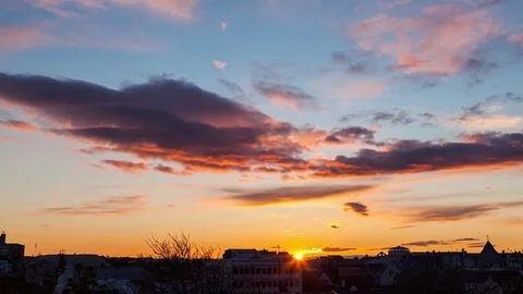Clouds in pink and orange sky rolling over the city during sunset Stock Footage 73011368