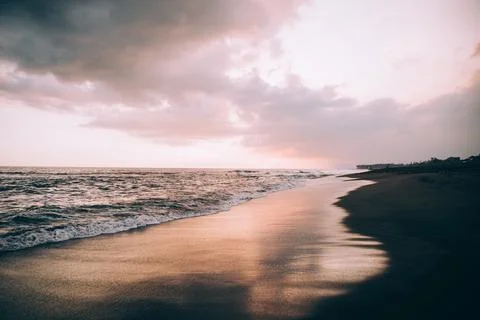 Clouds in a pink sky over wave soaked beach 스톡 사진