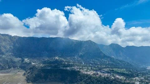Clouds pour over the ridgeline behind Cemoro Lawang, soft light painting forests Stock Photos