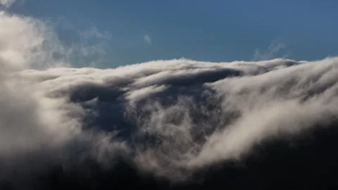 Clouds pouring over mountainside in real time Stock Footage 336939535