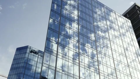Clouds reflect on the windows of a mirrored office building. Timelapse 動画素材 248912031