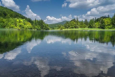Clouds reflected in a lake surrounded by hills and green lush forest, Plitvic Stock Photos