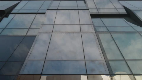Clouds reflected at large glass windows of modern office building, bottom view Stock Footage 259554028