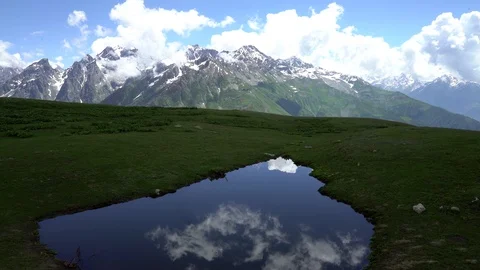 Clouds reflected  in mountain lake. Snow capped mountain peaks in the background Stock Footage 115964090