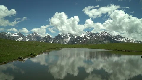 Clouds reflected  in mountain lake. Snow capped mountain peaks in the background Stock Footage 115964660