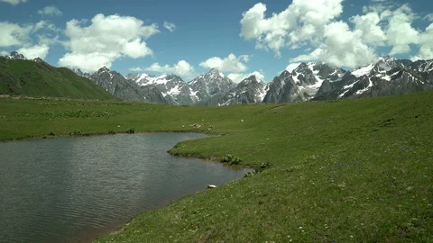 Clouds reflected  in mountain lake. Snow capped mountain peaks in the background Stock Footage 115964682