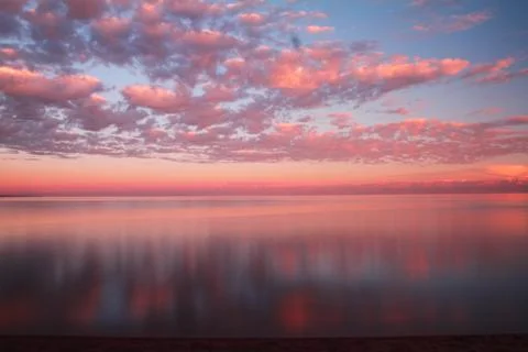 Clouds reflected on the water during sunset Stock Photos
