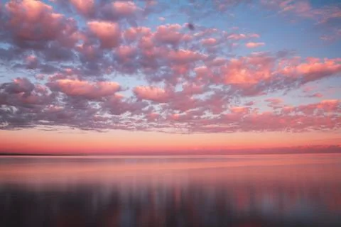 Clouds reflected on the water during sunset Stock Photos