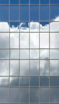 Clouds reflected in windows in the blue skyscraper office building Stock Photos
