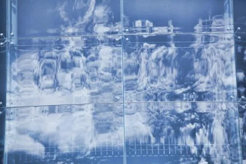 Clouds reflected in windows of modern office building Stock Photos