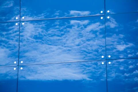 Clouds reflected in windows of modern office building Stock Photos